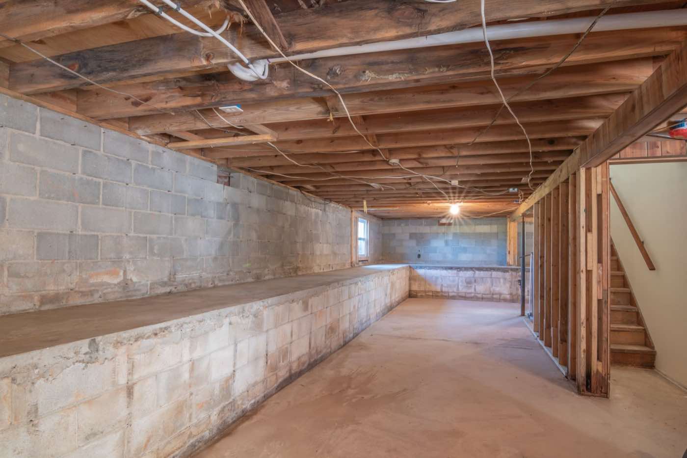 An unfinished basement with cinder-block walls and exposed floor joists