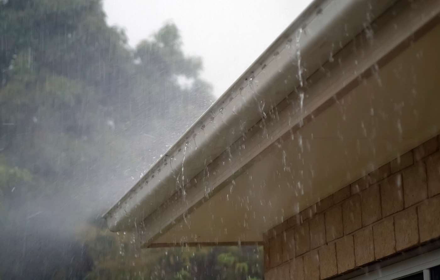 Heavy rain sheeting off the edge of a house gutter