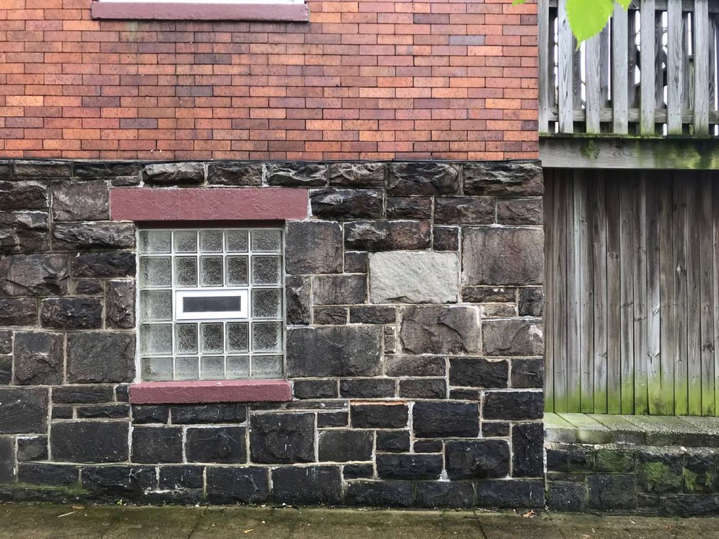 A stone foundation wall with a small basement window set into it